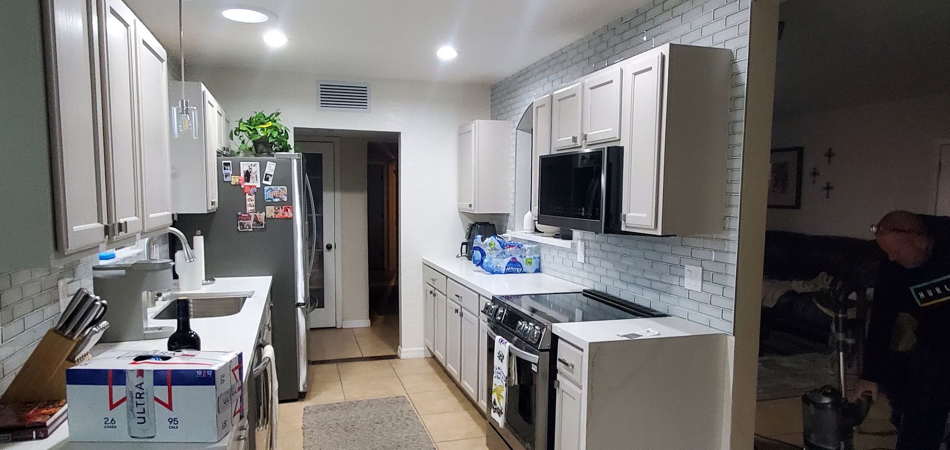 A man is standing in a kitchen with a vacuum cleaner.
