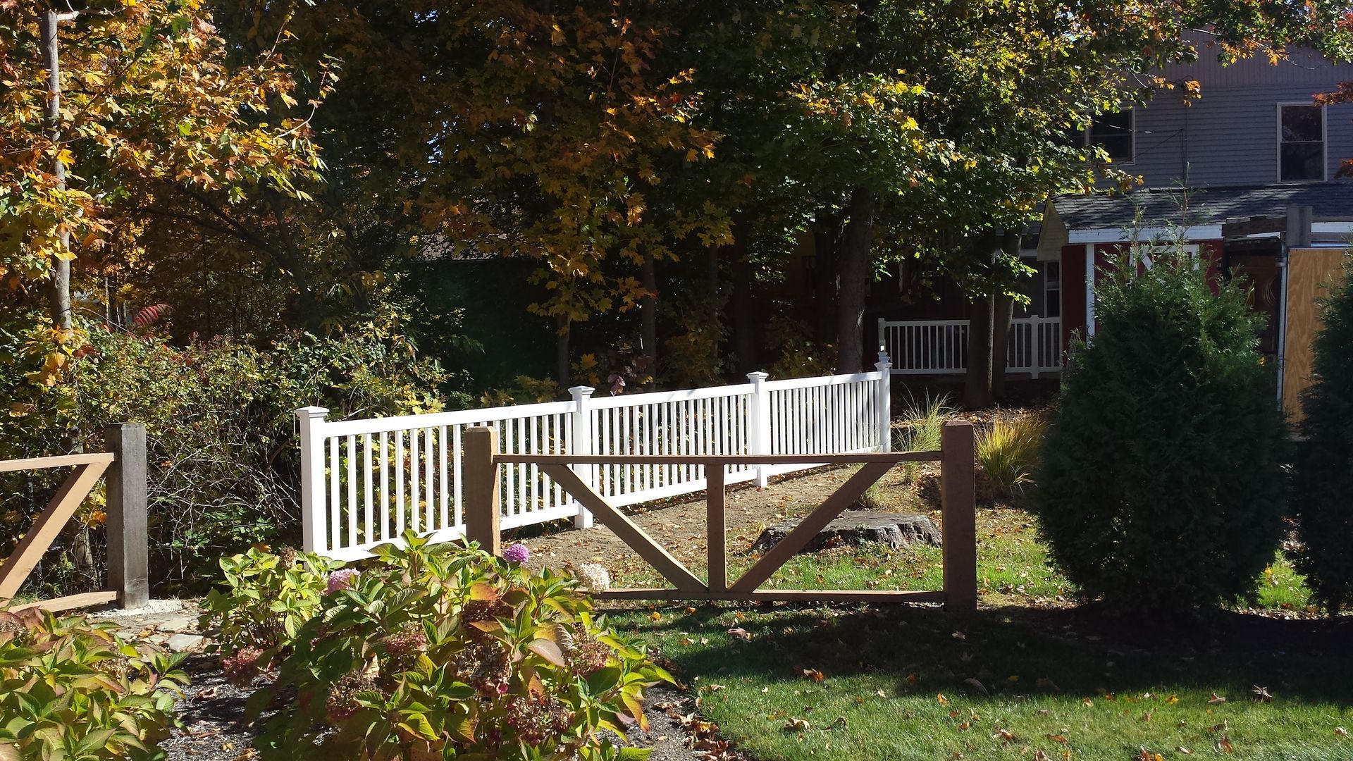 A white fence with a wooden gate in front of a house