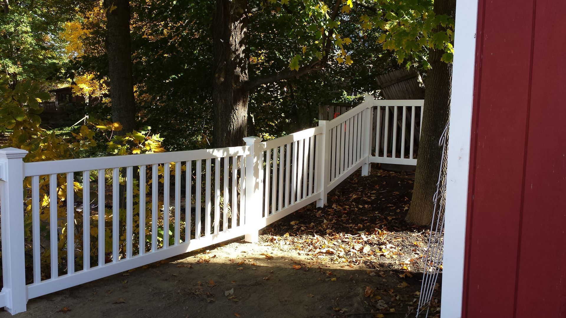 A white fence with a red building in the background