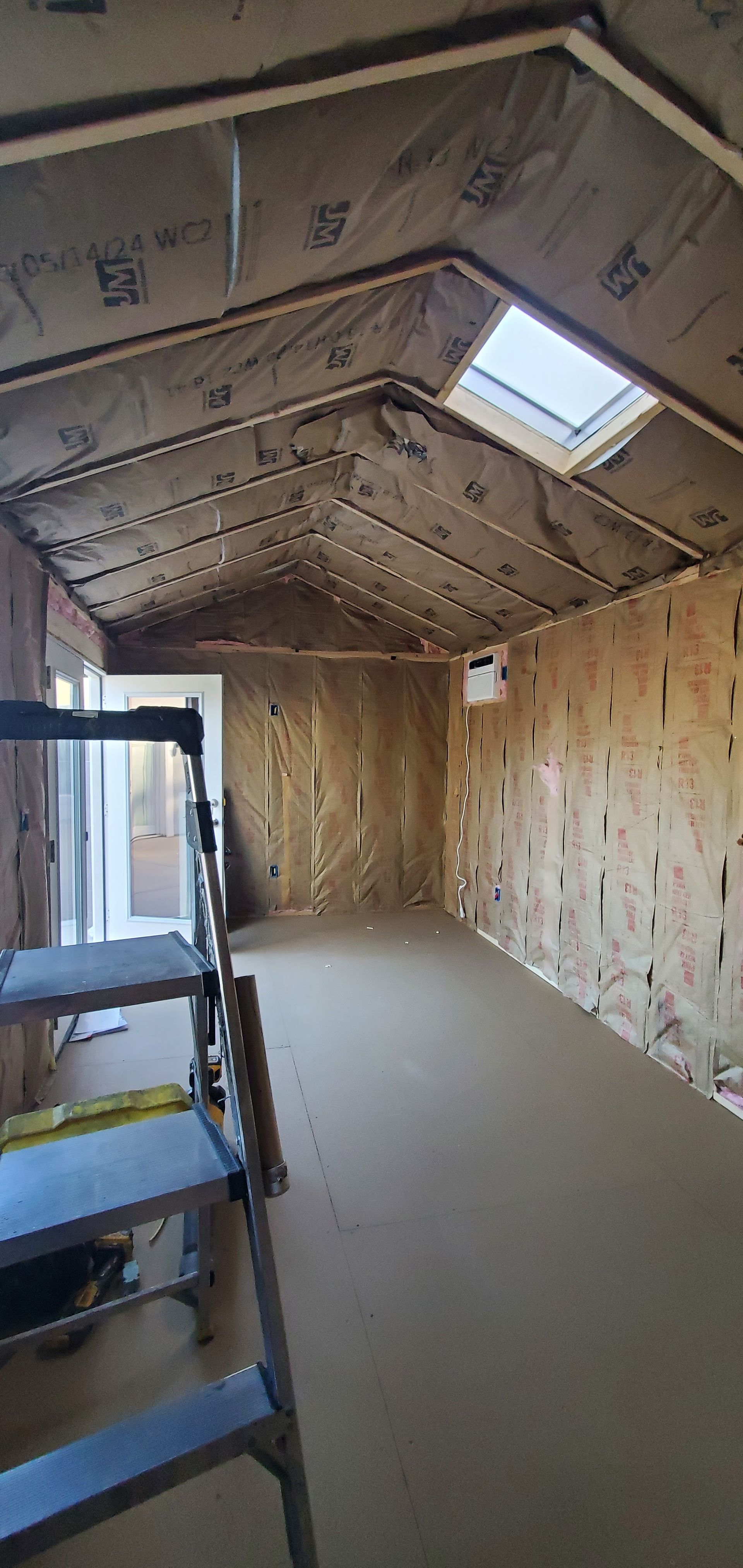 A room with a ladder and a skylight in the ceiling.
