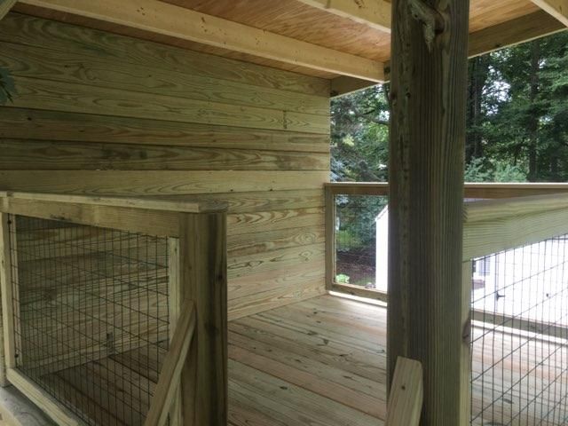 A wooden house with a fence around it and a wooden deck.