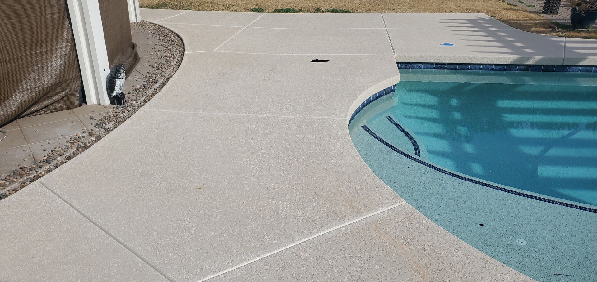 A swimming pool with a concrete deck next to it.