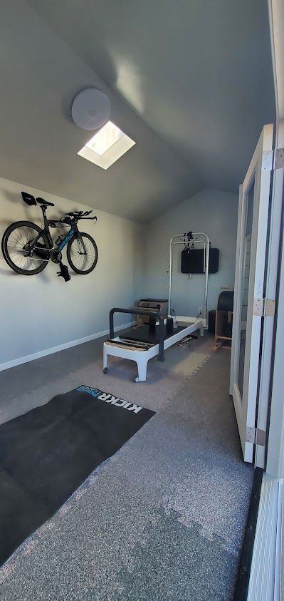 A room with a bicycle hanging on the wall and a treadmill.