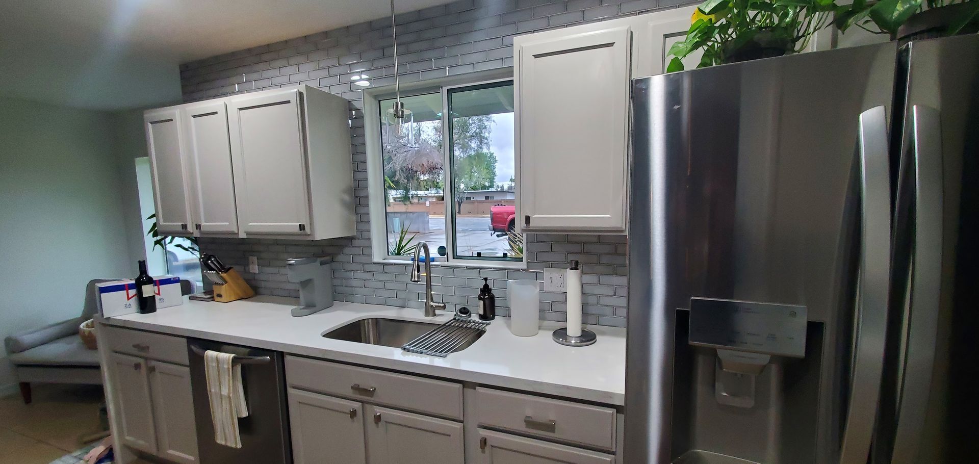 A kitchen with white cabinets , stainless steel appliances , a sink , and a refrigerator.