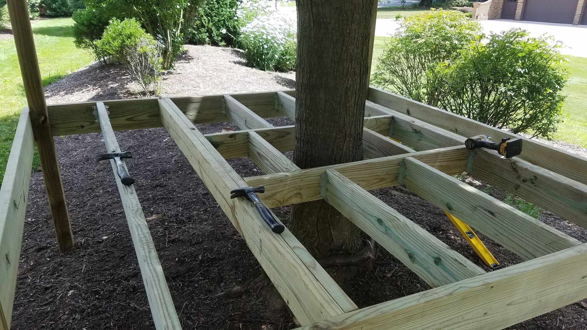 A wooden deck is being built around a tree.