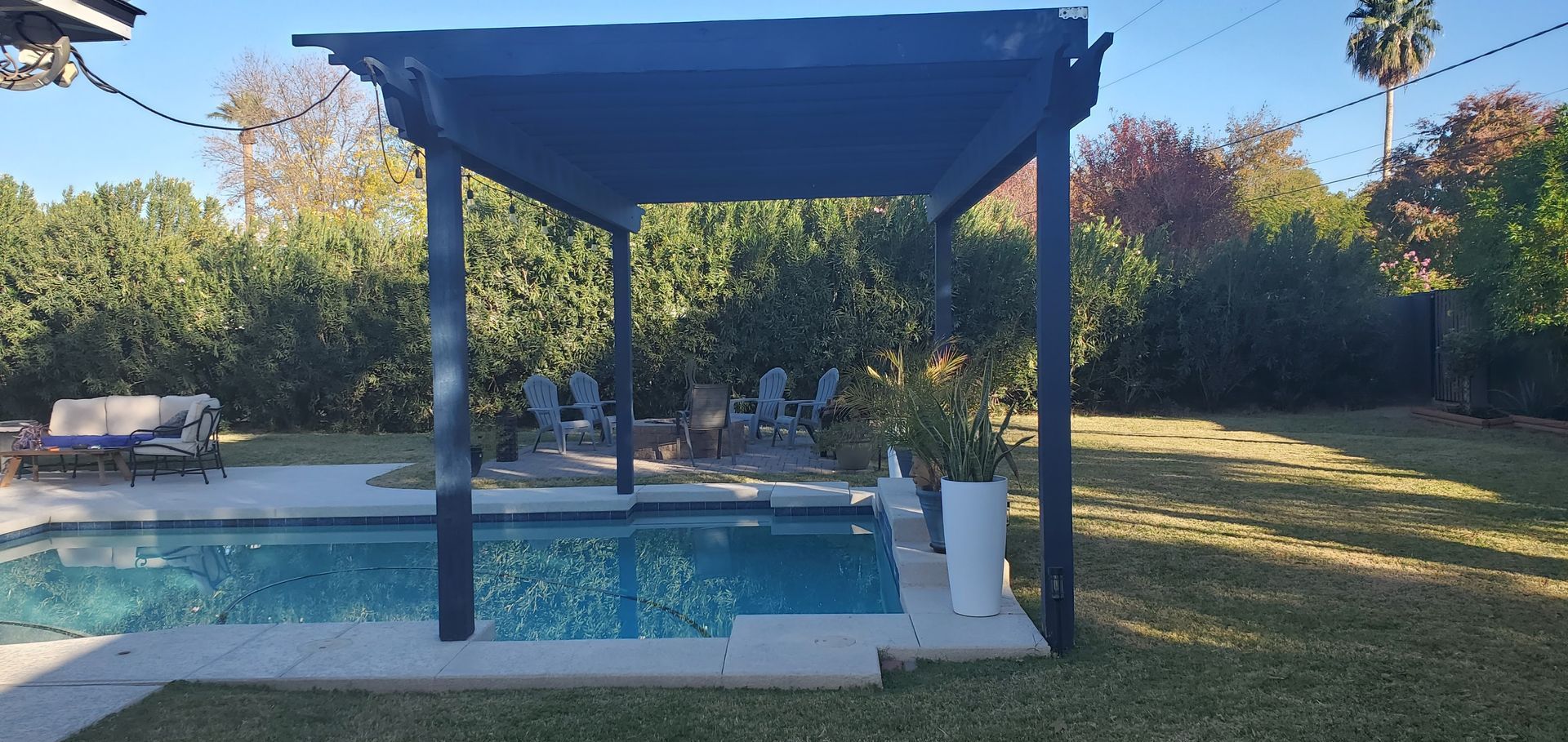 A swimming pool with a pergola in the backyard