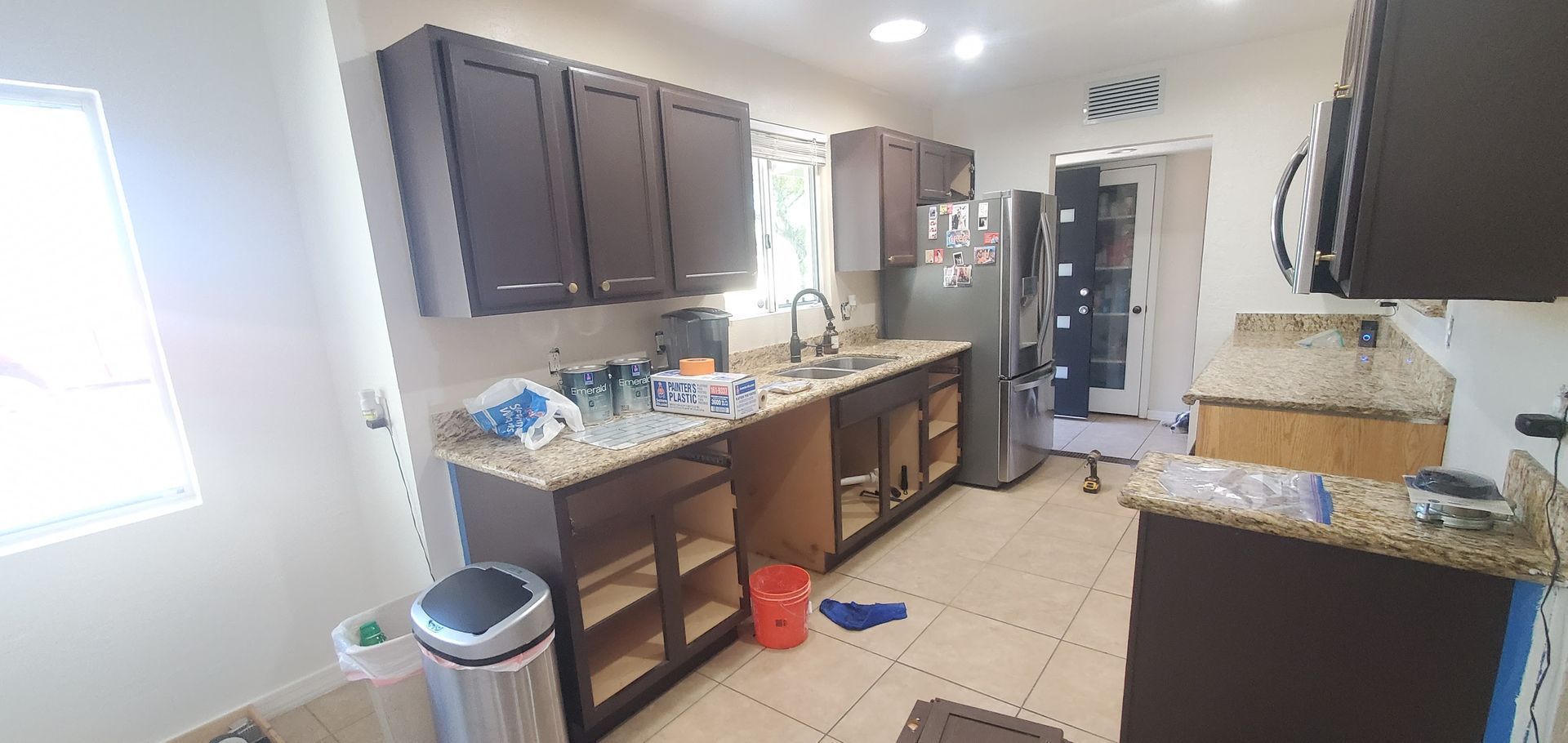 A kitchen with a trash can in the middle of it.