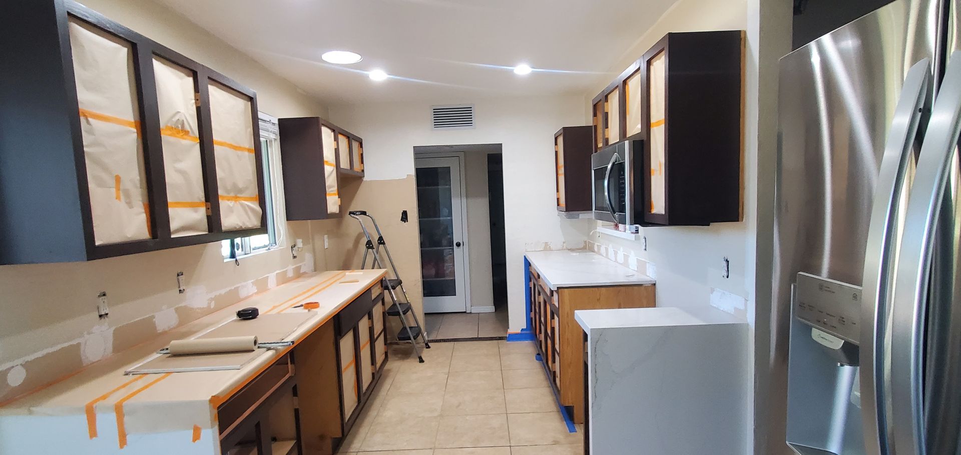 A kitchen is being remodeled with stainless steel appliances and wooden cabinets.