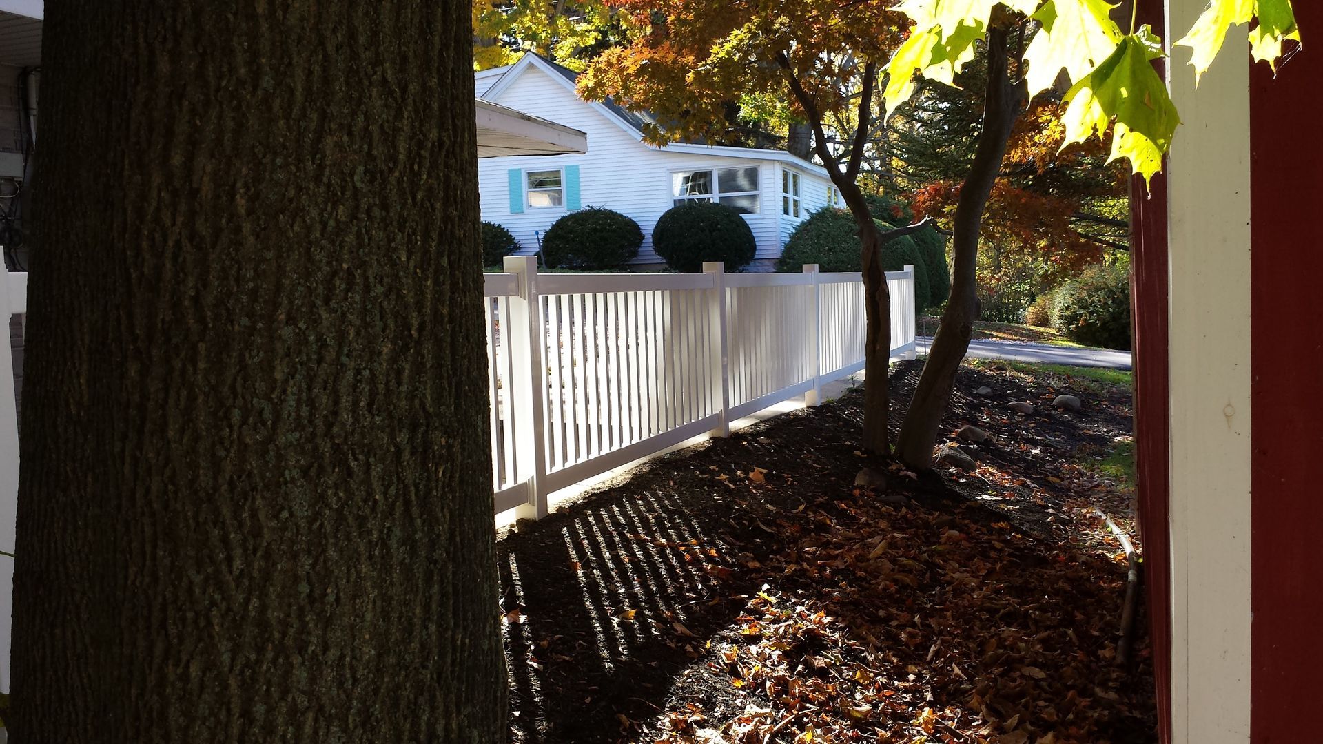 A white picket fence is surrounded by trees and leaves