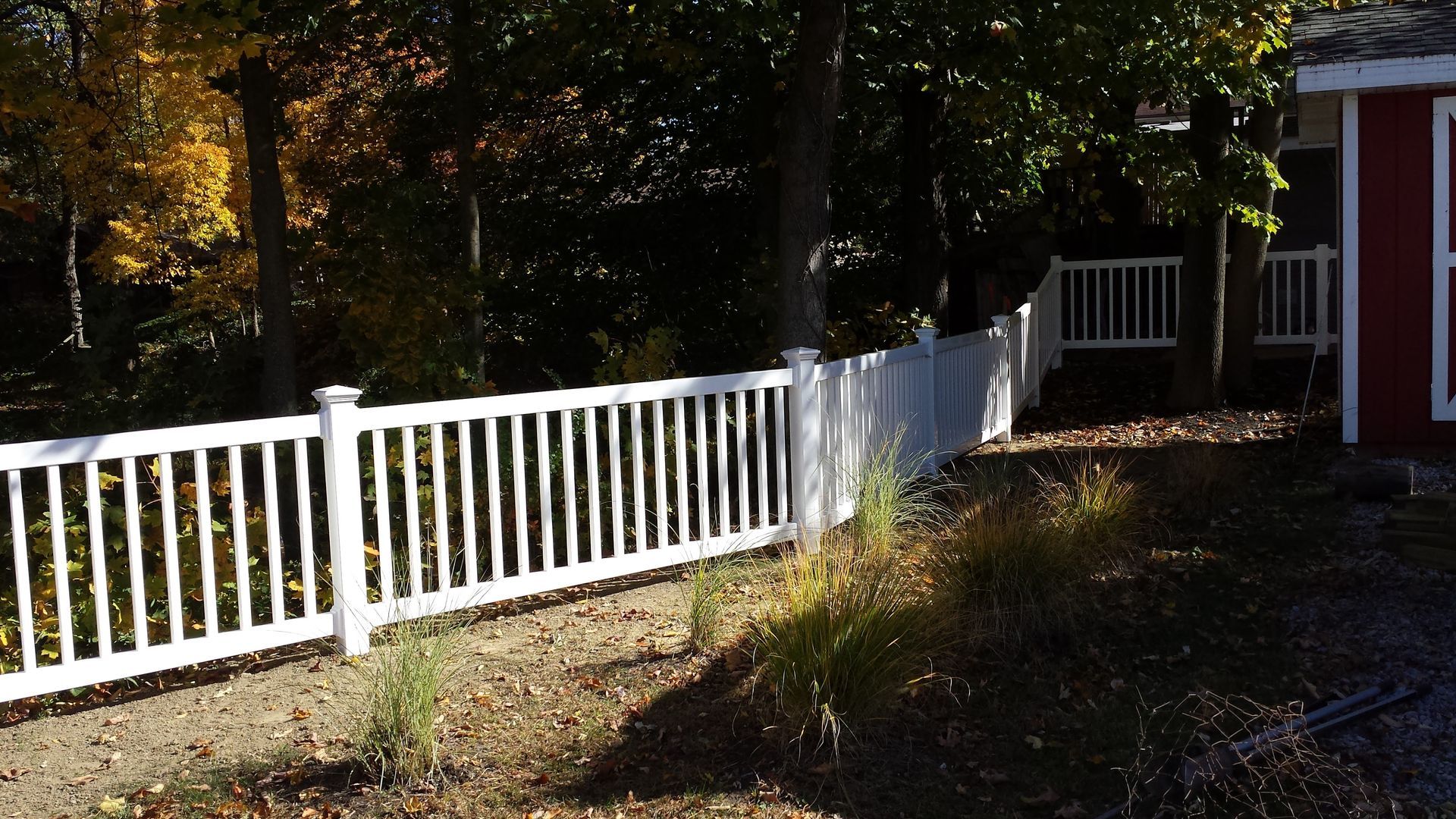 A white fence with a red barn in the background