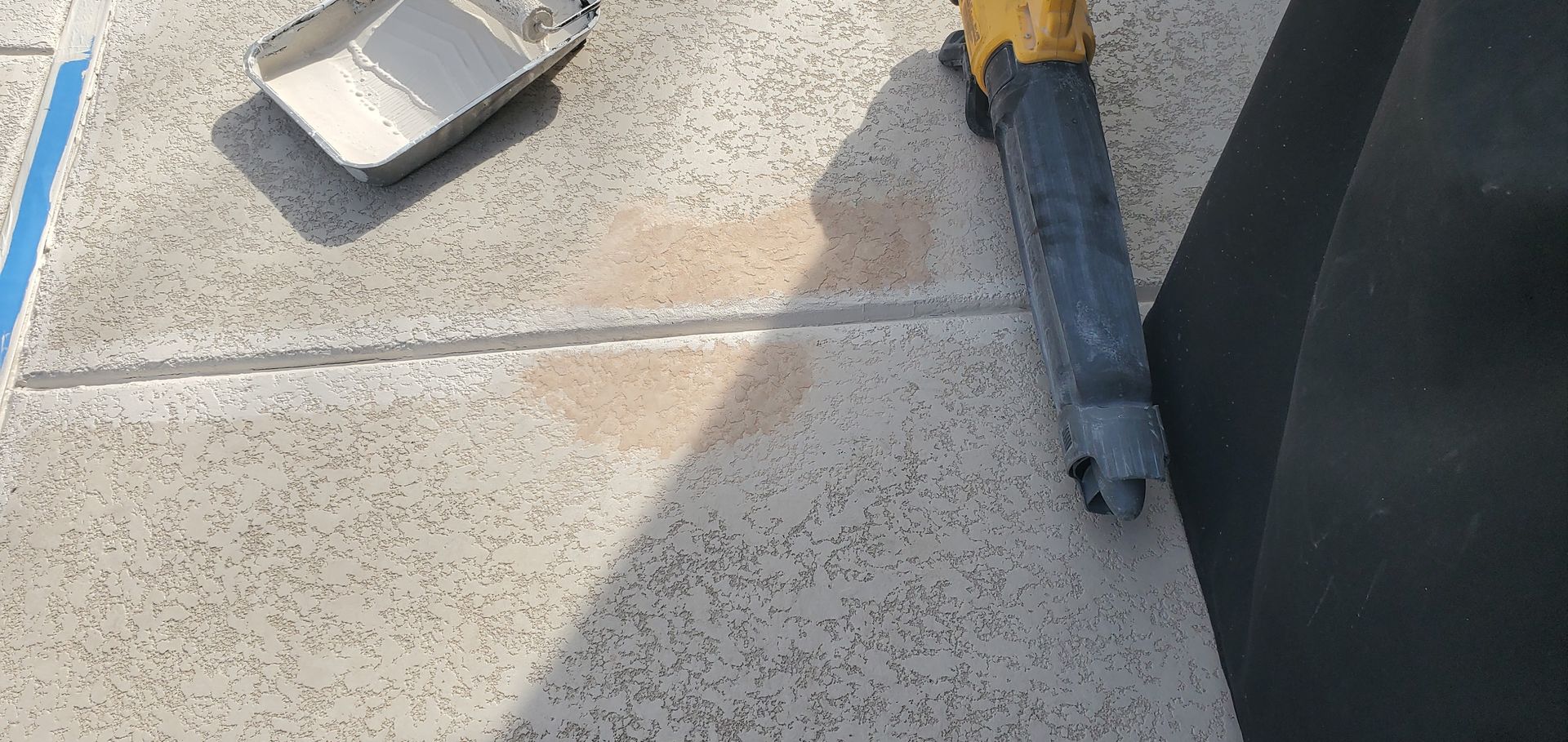 A person is working on a concrete floor with a tool.