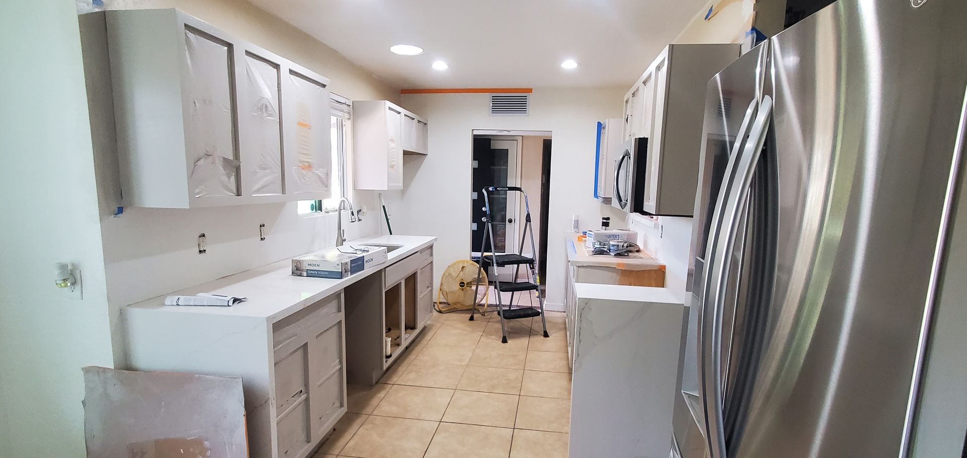 A kitchen with stainless steel appliances and white cabinets is being remodeled.
