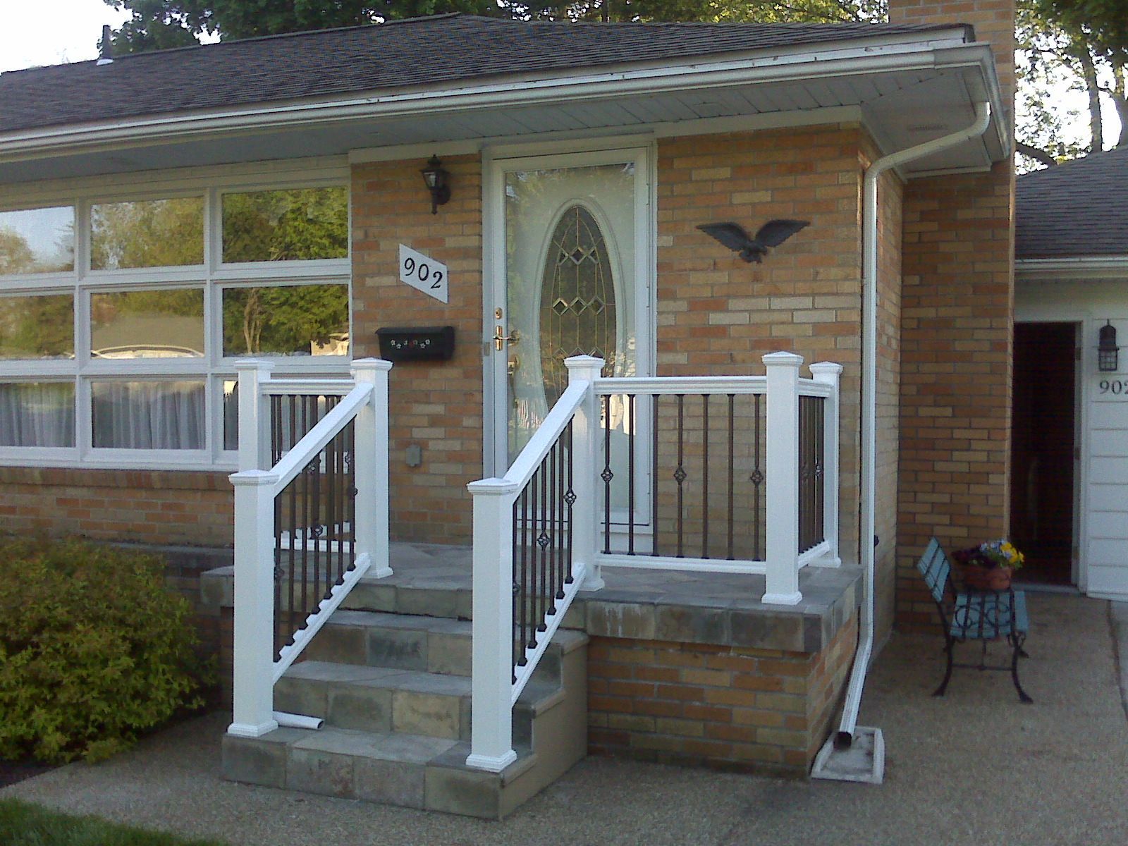 A brick house with a white railing and stairs