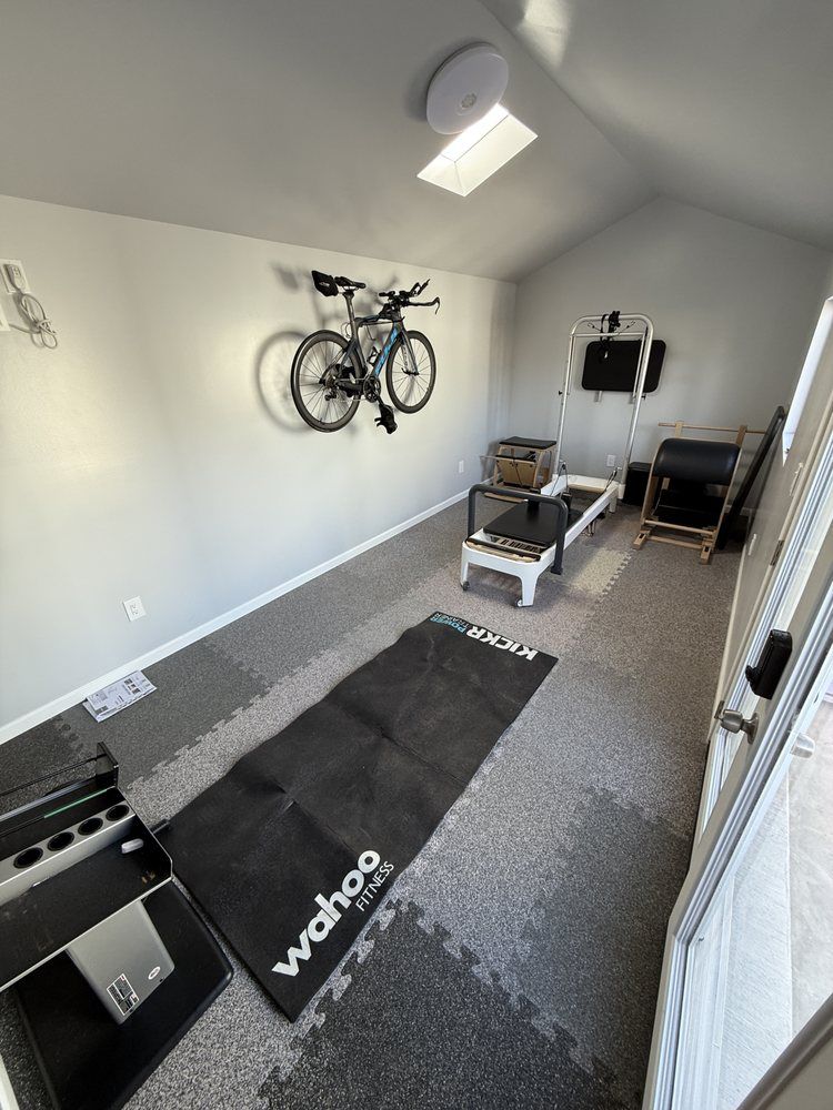 A room with a bicycle on the wall and a mat that says wahoo on it.