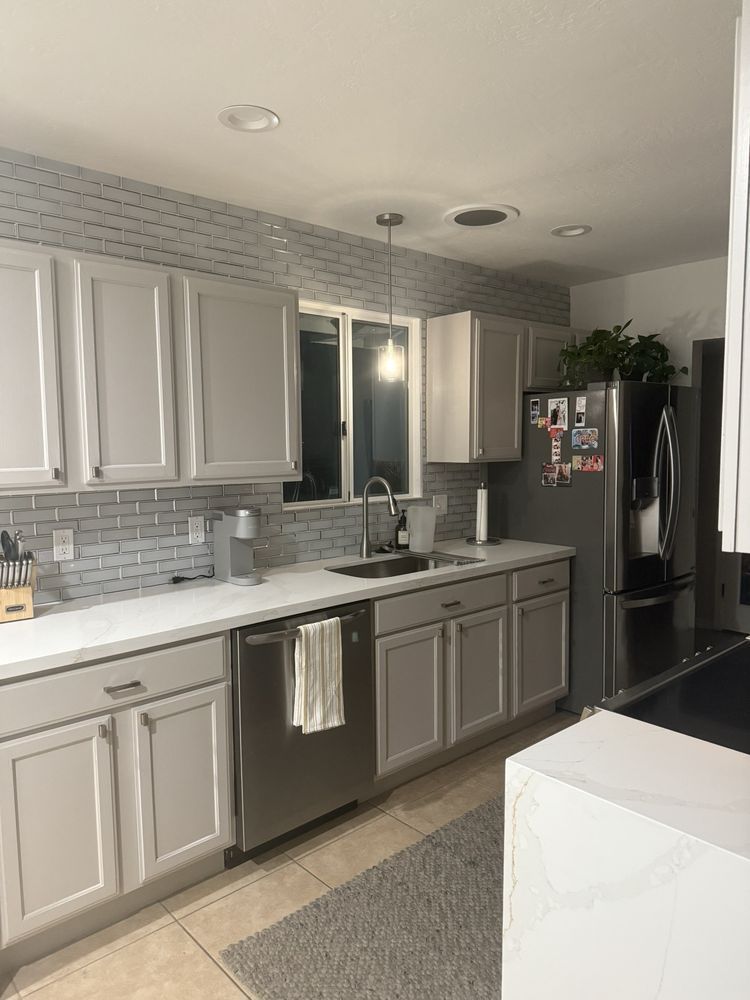 A kitchen with white cabinets , stainless steel appliances , a sink , and a refrigerator.