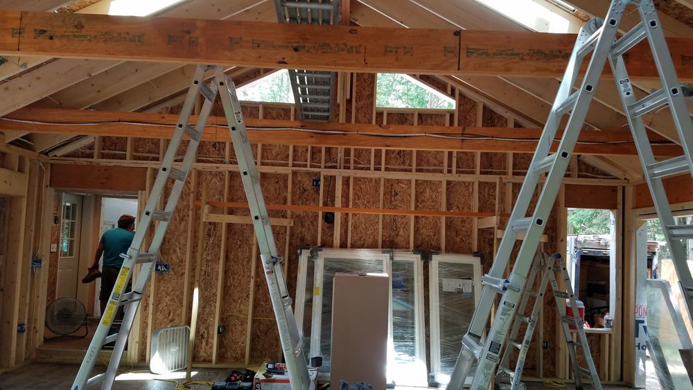 A man is standing on a ladder in a room under construction.