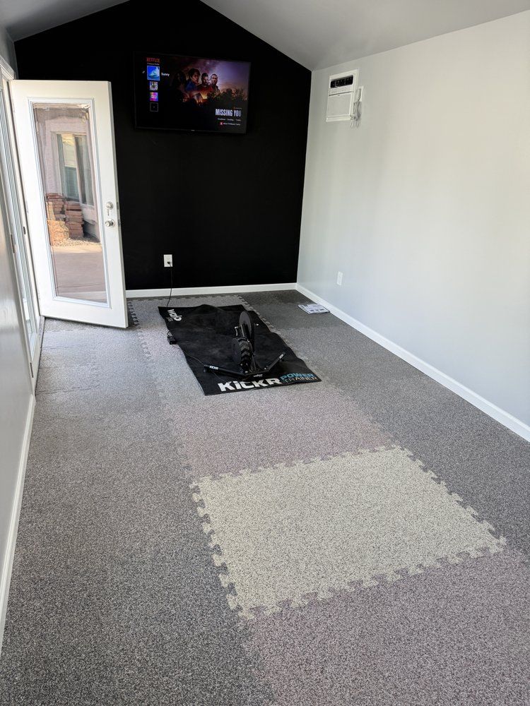 A room with a tv on the wall and a puzzle mat on the floor.