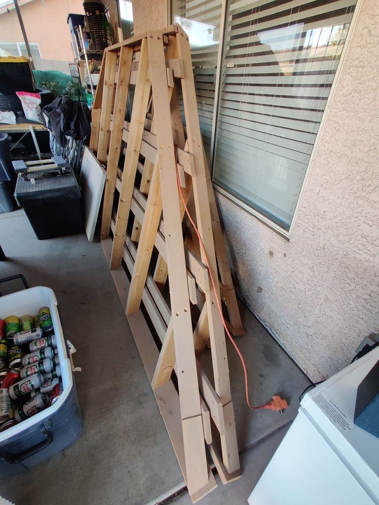 A wooden ladder is sitting on a patio next to a window.