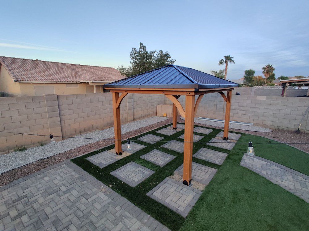A wooden gazebo with a blue roof is sitting on top of a brick patio.