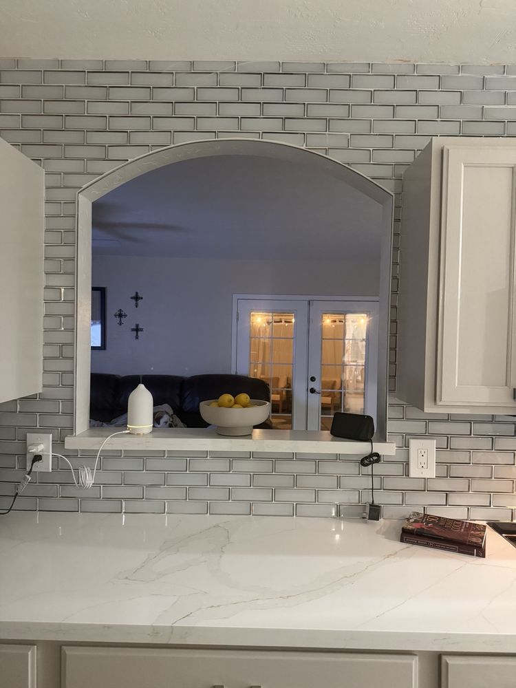 A kitchen with white cabinets and a white brick wall.