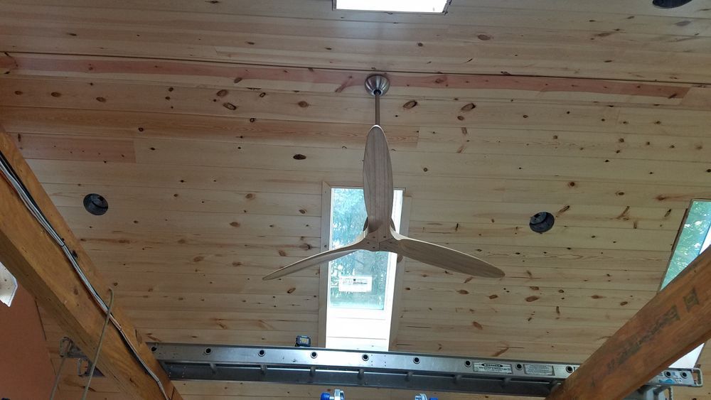 A ceiling fan is hanging from the ceiling of a wooden building.