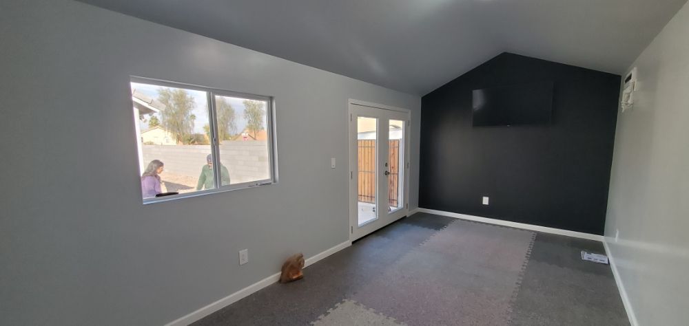 An empty living room with a vaulted ceiling and sliding glass doors.