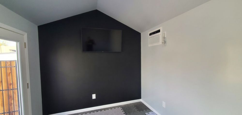 A room with black walls and a flat screen tv on the wall.