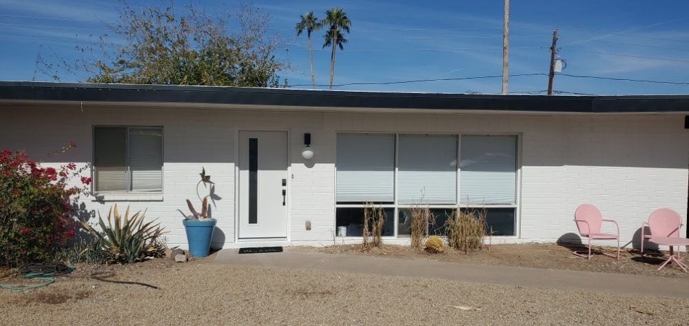 A white house with pink chairs in front of it