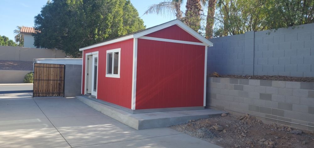 A red shed with white trim sits in a driveway