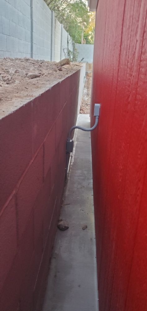 A red wall with a power outlet on it next to a sidewalk.