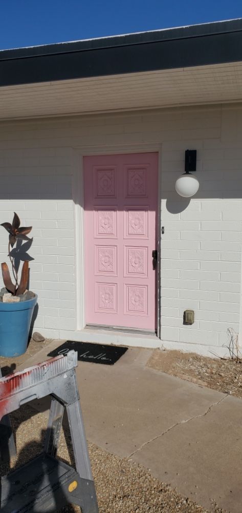 A pink door is painted on the front of a white house.