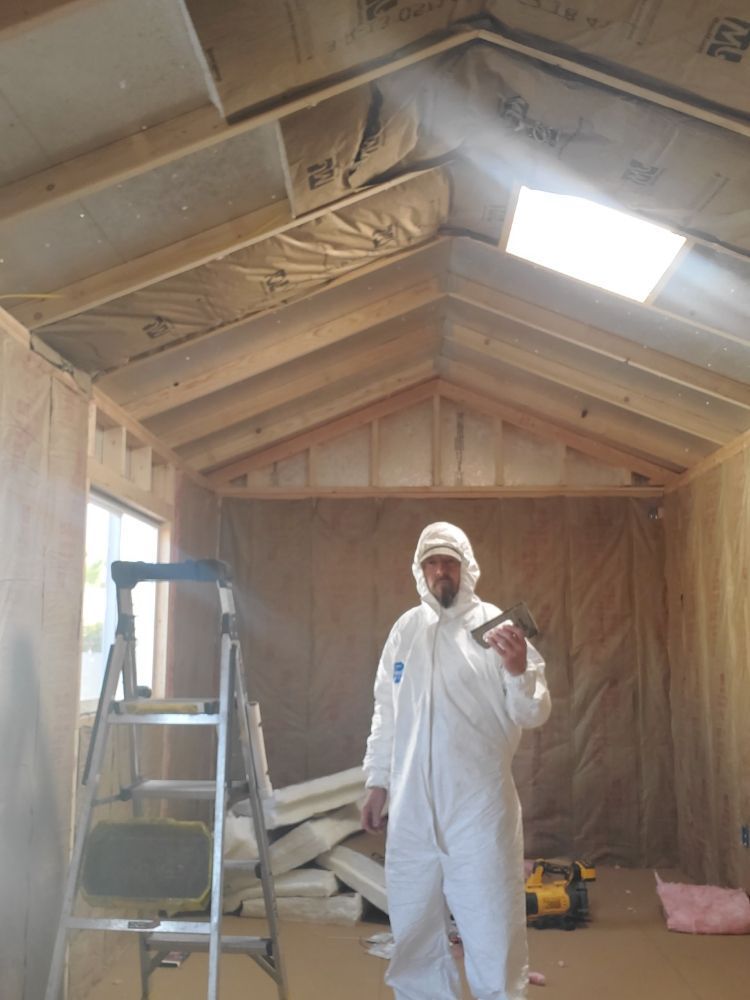 A man in a white suit is standing in a room with a ladder.