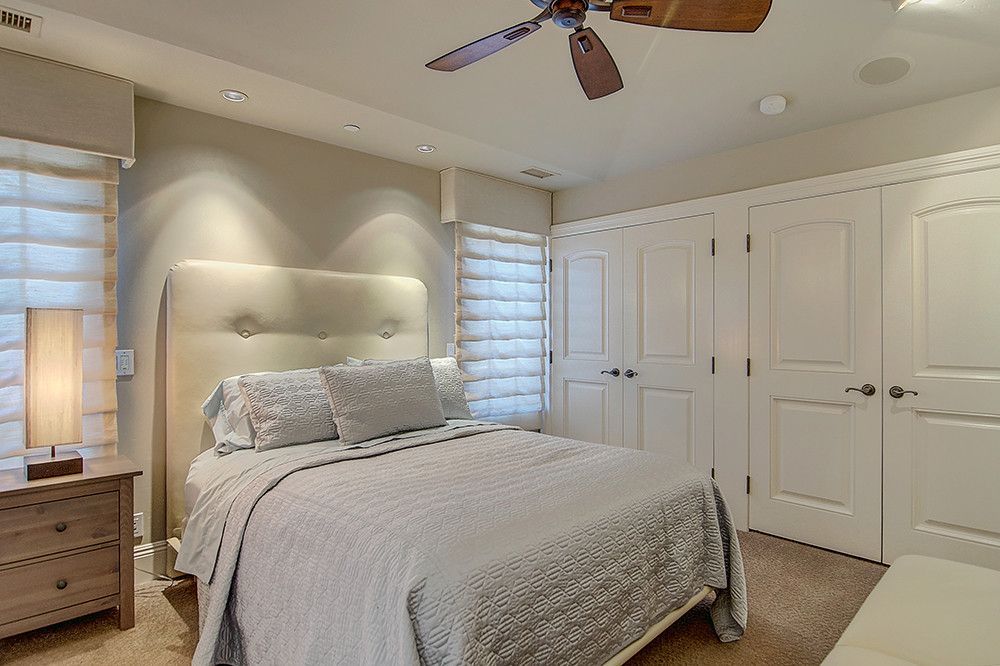 Bedroom with a bed, nightstand, closet, and window with shades. The room is neutral in color.