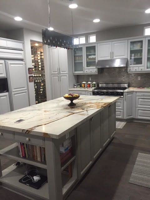 Elegant white kitchen with a large island featuring a light-colored mar