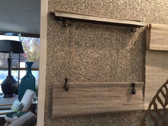 A wall-mounted clothes drying rack with a wooden shelf and hanging hooks against a speckled wall.