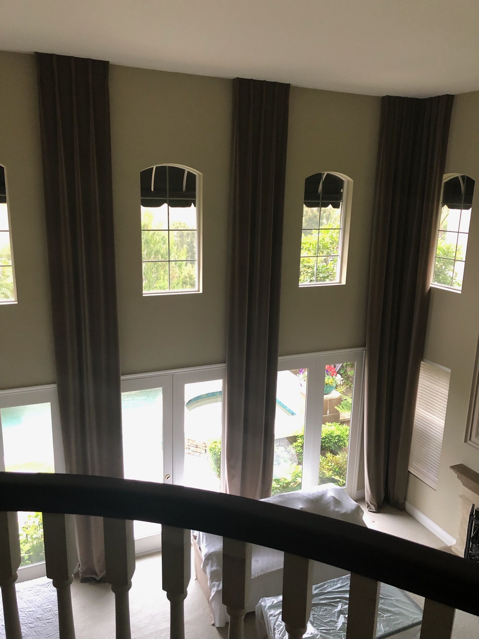 High-angle view of a two-story room with long, brown curtains. Sunlight 