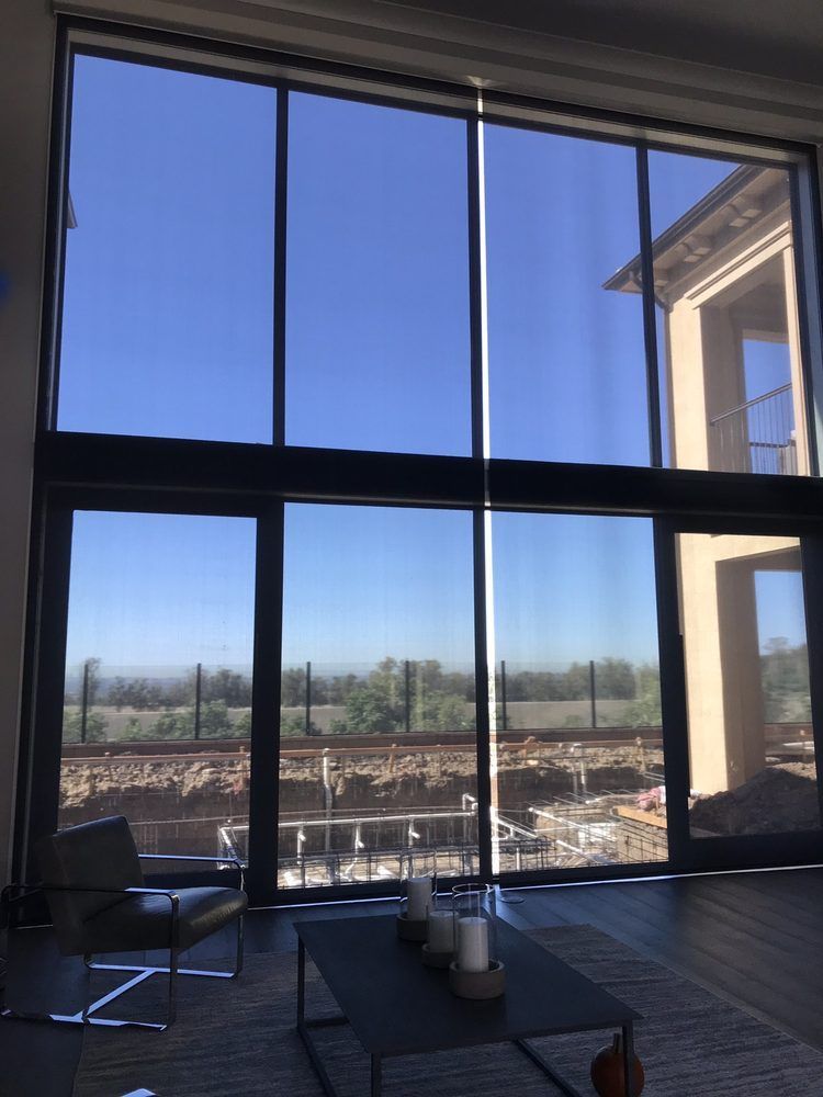 Large windows offer a view of a blue sky and construction site from a modern interior with furniture.
