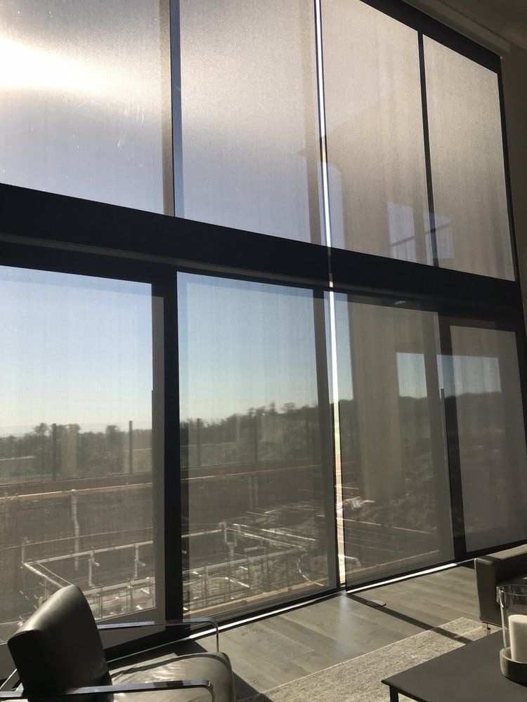 Large windows with sheer blinds, providing a view of an outdoor 