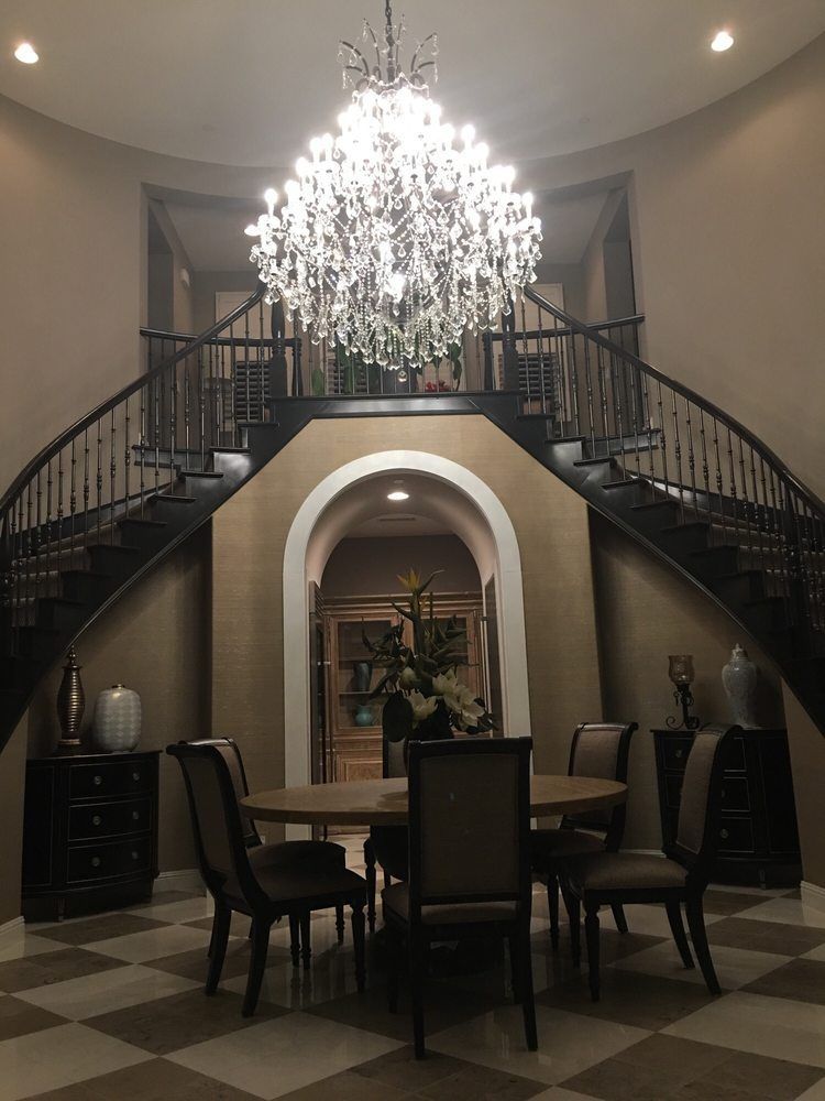 Grand foyer with a chandelier above a dining table, flanked by a s
