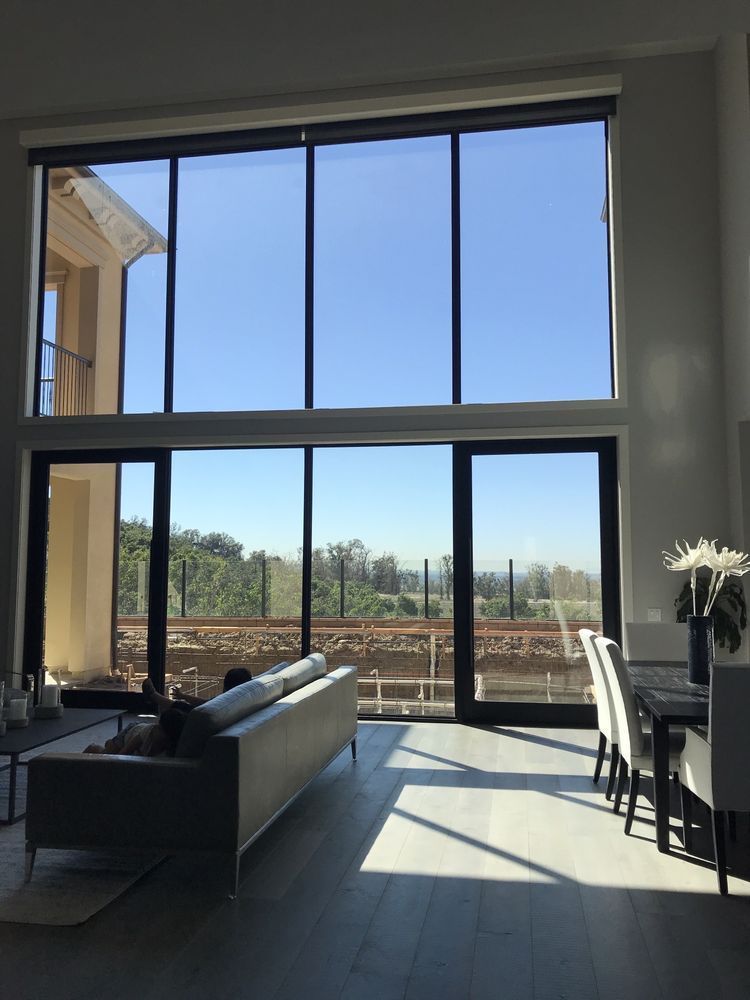 Large sunny living room with tall windows overlooking an outdoor view. I