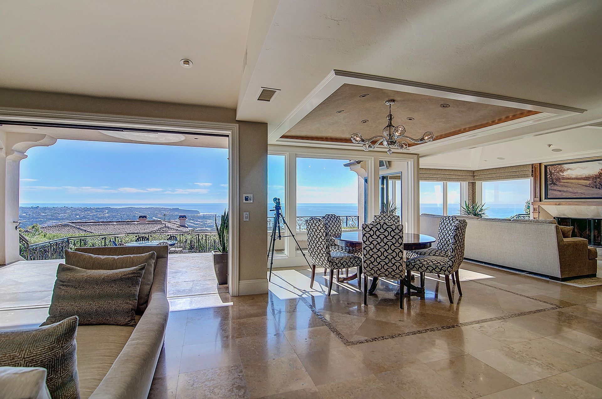 Spacious, light-filled living room with a dining area, featuring city and ocean views through large windows.