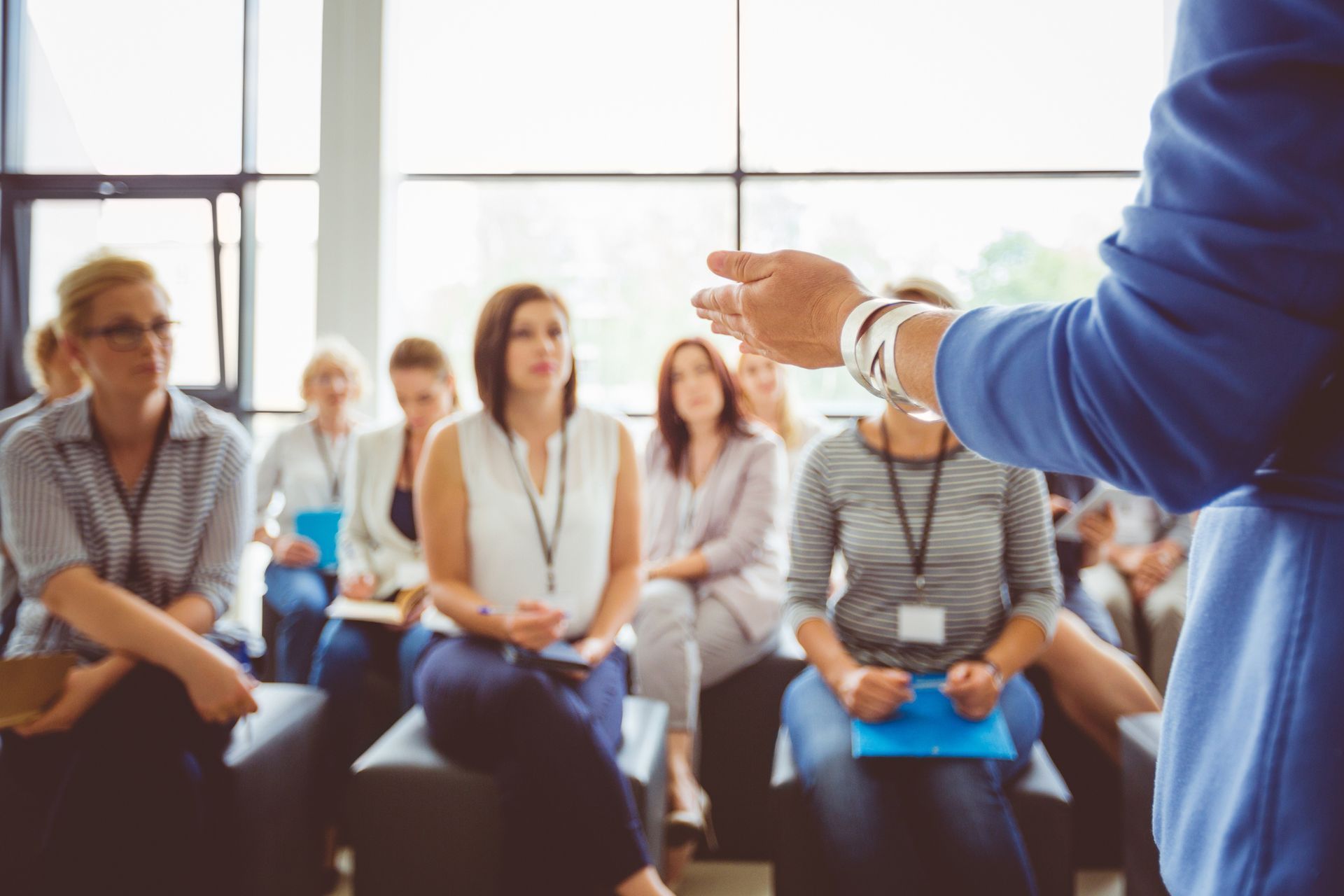 A woman is giving a presentation to a group of people sitting in a room.