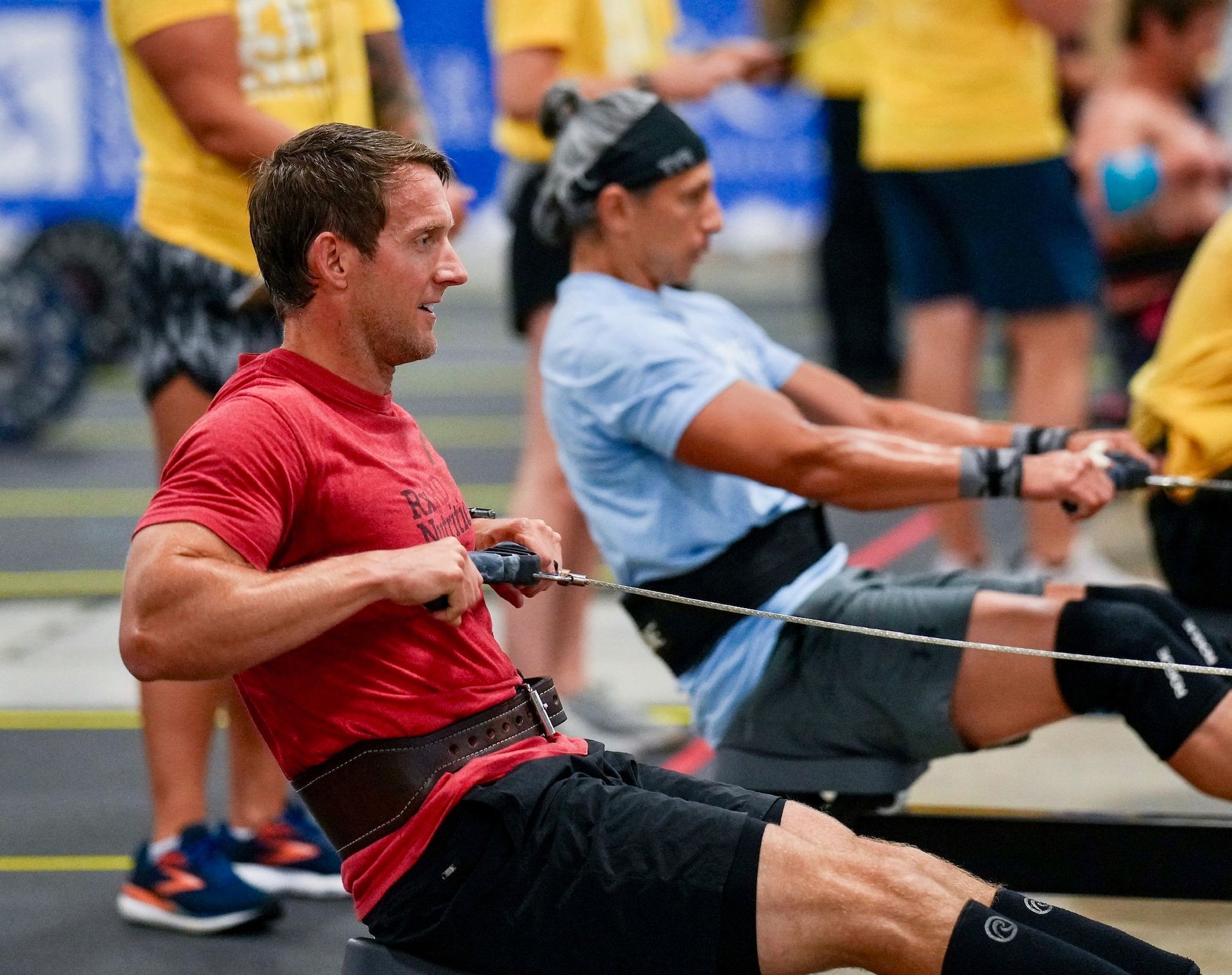 A man in a red shirt is rowing a rowing machine.