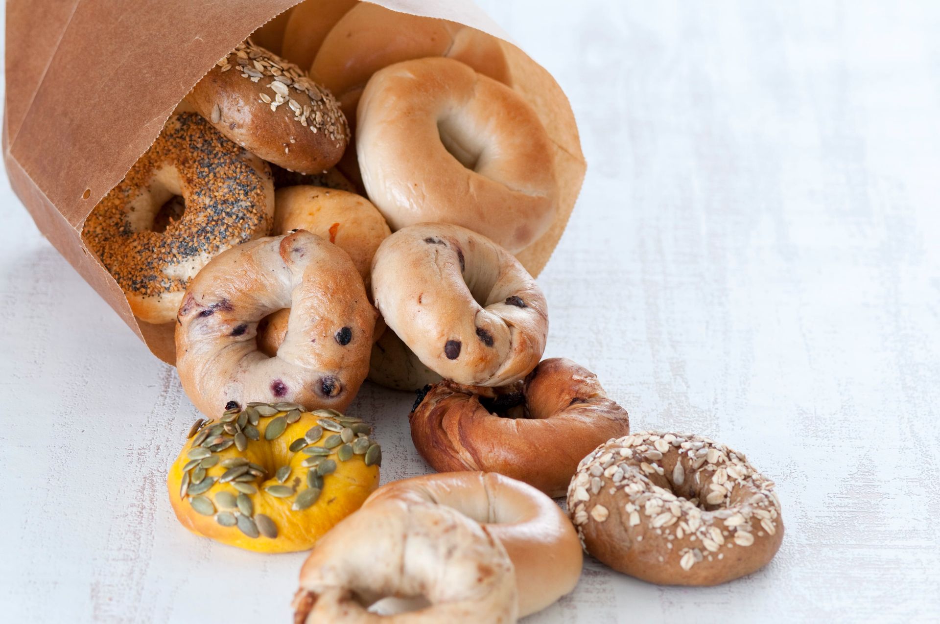 A bag of bagels is spilling out onto a table.