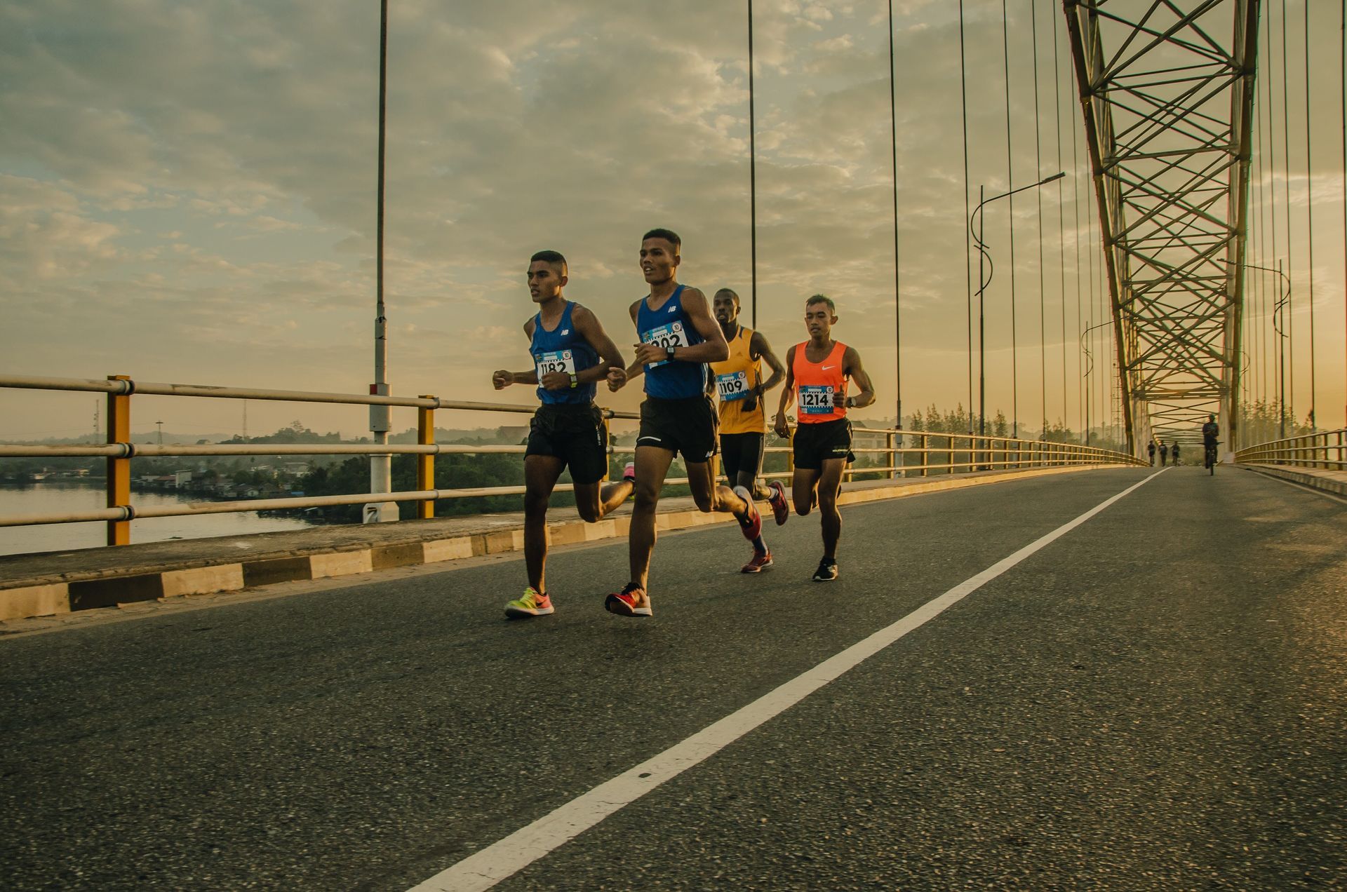 A group of men are running a marathon on a bridge.