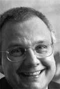 Auf einem Schwarzweißfoto lächelt ein Mann mit Brille.
