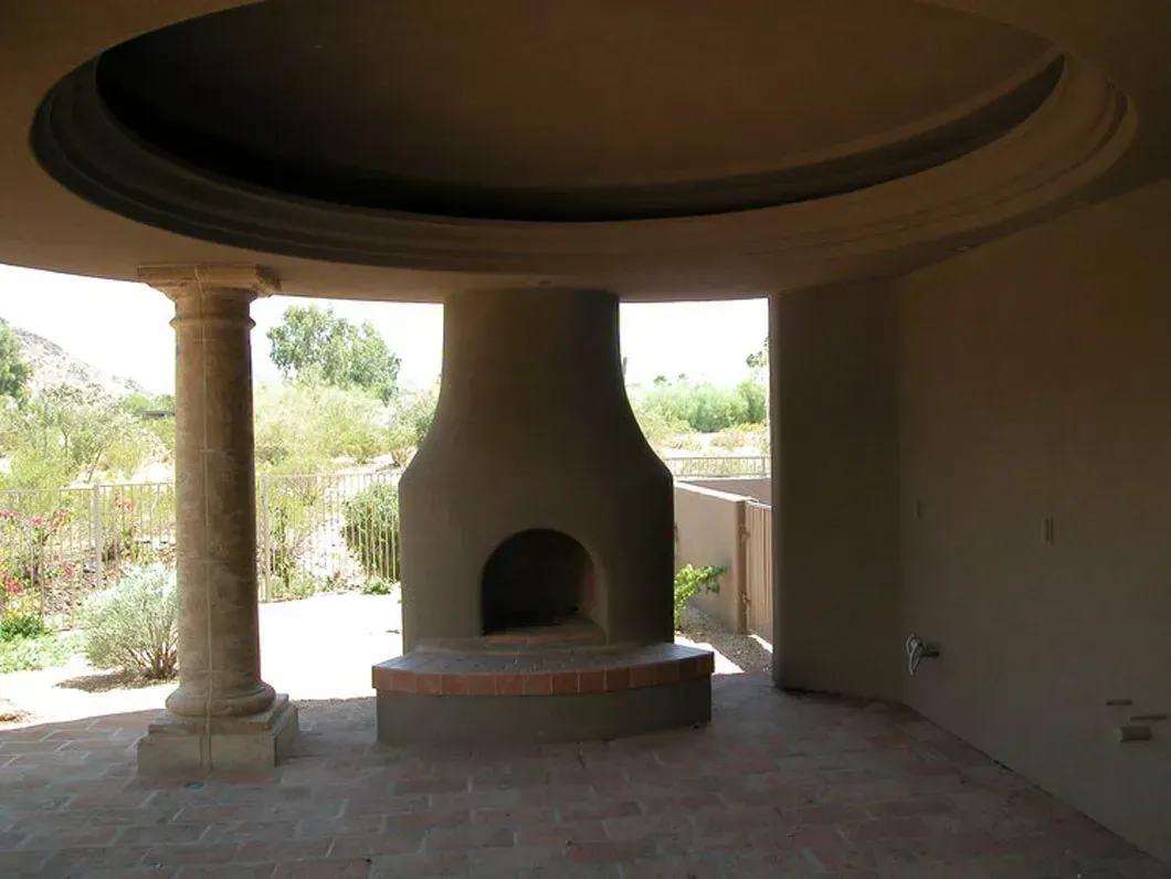 Covered outdoor patio with fireplace, columns, and brick flooring.