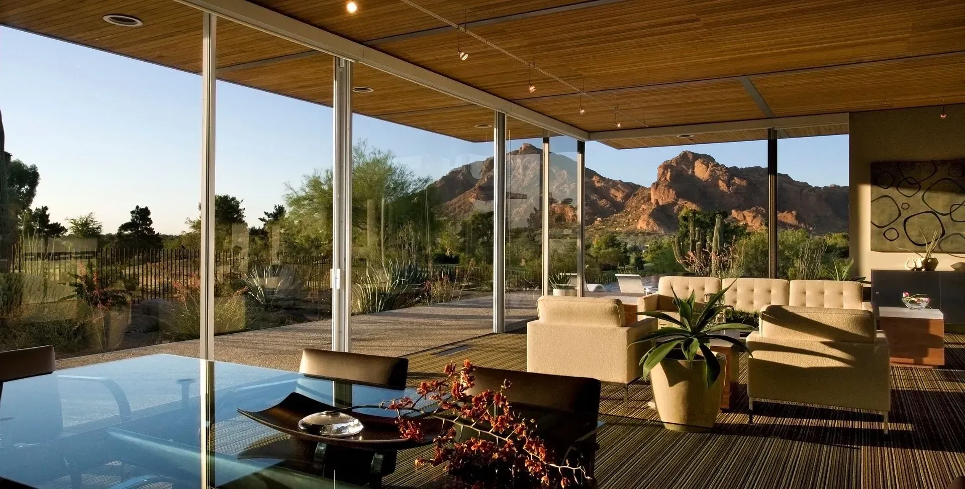 Modern home with floor-to-ceiling windows and view of mountains and desert landscape.