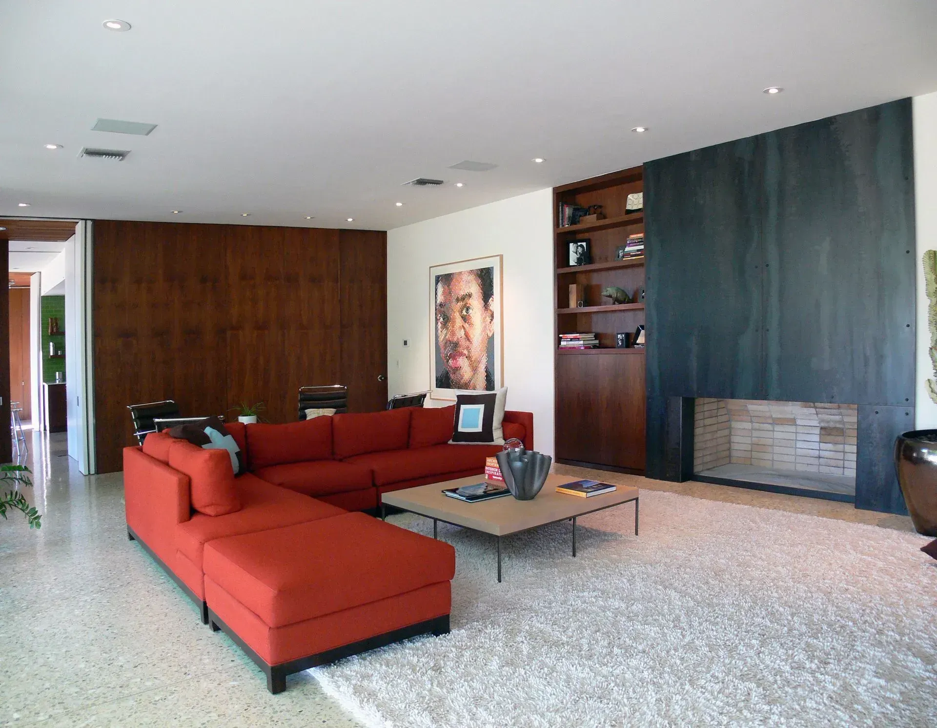 Modern living room with red sectional sofa, large rug, and fireplace.