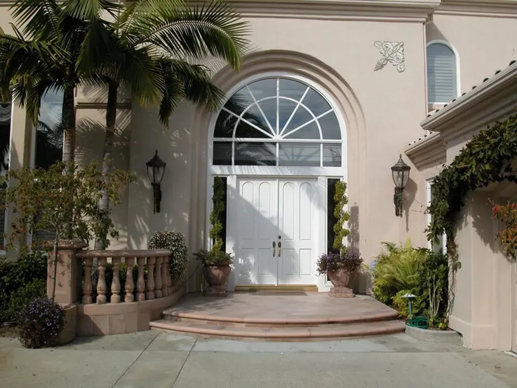 Exterior of a light-colored building with large arched entryway, double doors, and steps.